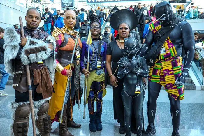 A family dressed up as characters from Black Panther, including a child dressed in T'Challa's Black Panther costume, with his hands in the Wakanda Forever pose
